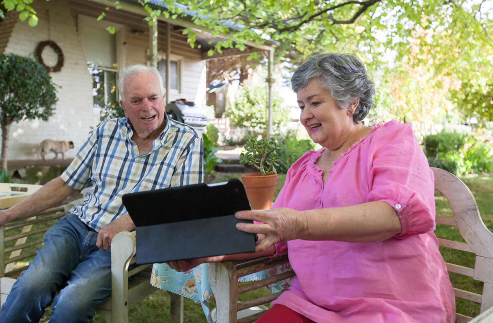 An Australian couple looking at a tablet in their garden